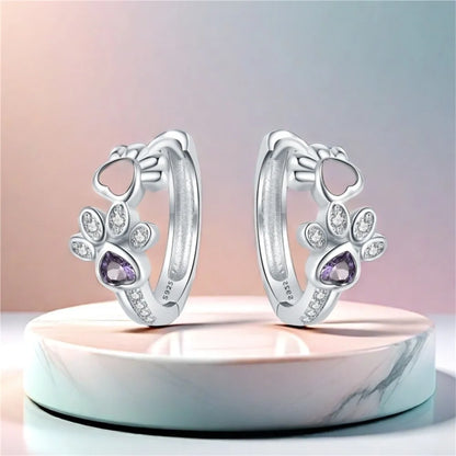 Oorbellen met pootafdruk in zilver met zirkonia en een hartvormige edelsteen.