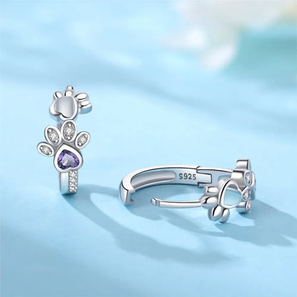 Oorbellen met pootafdruk in zilver met zirkonia en een hartvormige edelsteen.